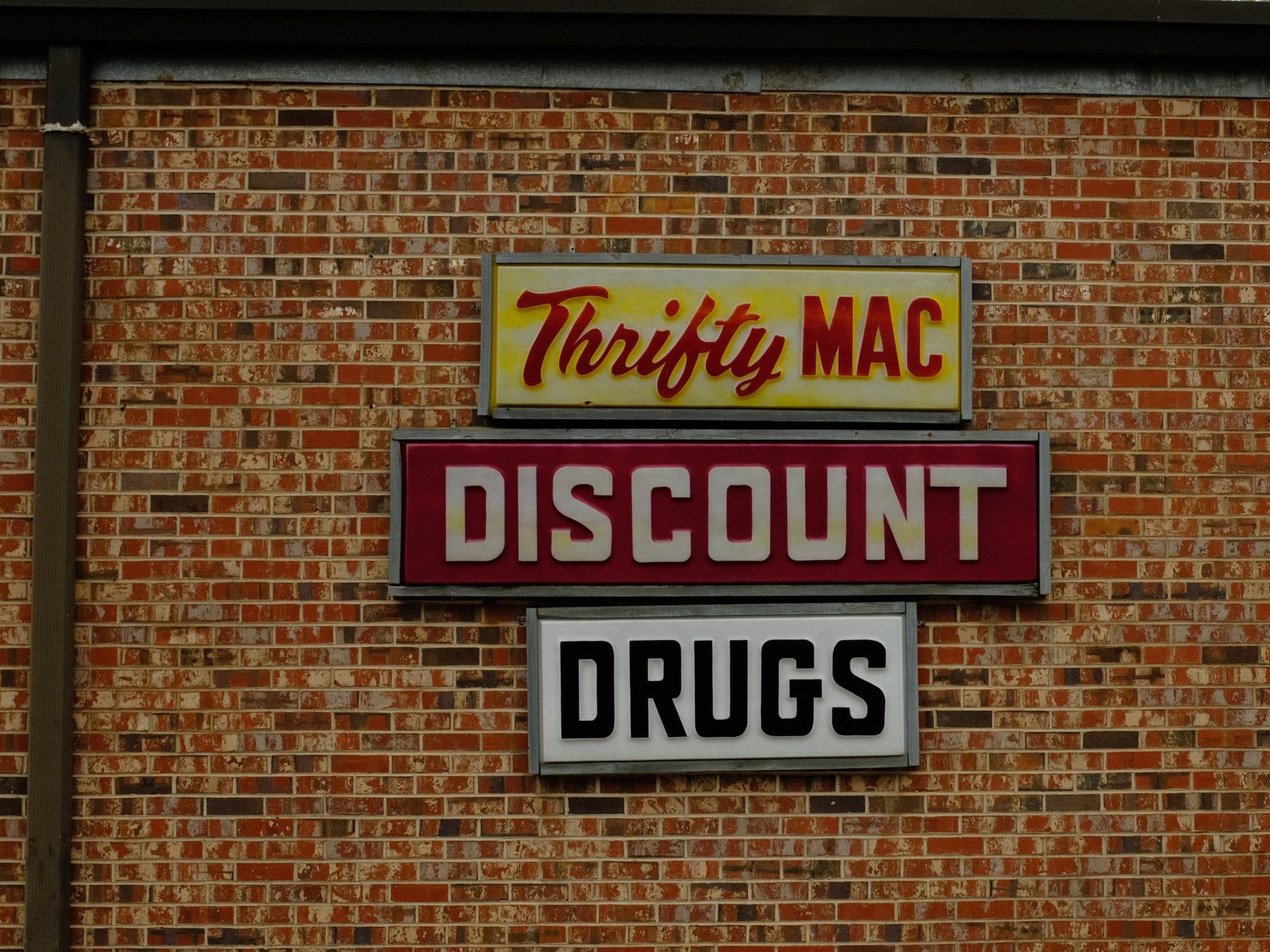 Thrifty Mac Discount Drugs sign on brick wall, vintage hand-lettered typography